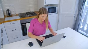 Online student typing on laptop computer at home on lockdown. Young blonde woman working on notebook pc in 4k stock video. Freelancer female doing distant work with fast internet connection