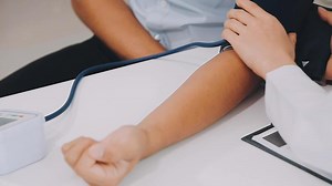 Download Doctor using sphygmomanometer with stethoscope checking blood pressure to a patient in the hospital. for free