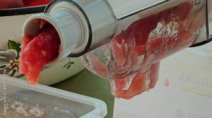 Making homemade fresh tomato juice with electric machine. Separation of bark and seeds from tomatoes juice.