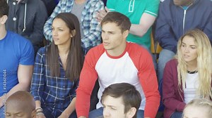 Sports fans in crowd expressing disappointment, watching live game in stadium