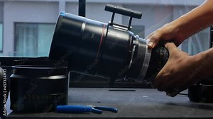 Human hands are rotating the focusing system of the big movie camera zoom lens for repairs.