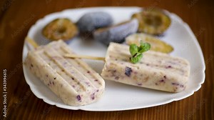 plum sweet homemade ice cream on a stick with slices of plum inside, in a plate