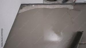 The process of leveling the self-leveling floor. Worker applying epoxy and polyurethane flooring system. Roll out the self-leveling floor with a needle roller.