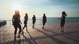 Zumba class dancing at the sunrise near the beach. slow motion, steadycam shot