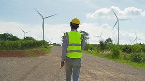 Portrait of Asian windmill engineer man, worker working on site at wind turbines field or farm, renewable clean energy source. Eco technology for electric power. industry nature environment. People