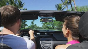 Car couple driving on road trip travel vacation in convertible. Young romantic couple on travel holidays vacation laughing smiling having fun. Man driver behind steering wheel. RED EPIC, SLOW MOTION.