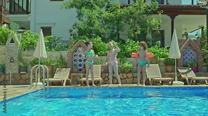 A group of little boys and girls dancing and having fun by the pool.Happy little kids in outdoor swimming pool spend summer vacation at hotel. Happy kids on vacation.