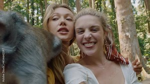 pov two women using smartphone video chat posing with monkey sitting on shoulder best friends having fun with monkeys sharing adventure at wildlife zoo tourists travel bali Stock Video