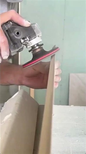 sanding and smoothing the edges of a ceramic tile using an electric angle grinder for a clean finish