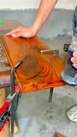 cutting a thick wooden plank using a circular saw with a metal guide rail on a workbench in a shop