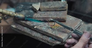jeweler solders a silver blank with a gas burner in the process of creating a jewelry ring