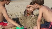 Beach activity. Children creating sandcastle