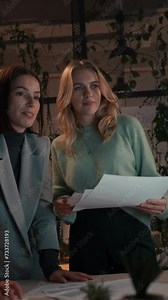 Happy girls looking at the computer screen and discussing something at the evening office