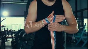 Boxer binds his hands with a bandage before the battle. My husband trains in the gym. The champion is boxing.