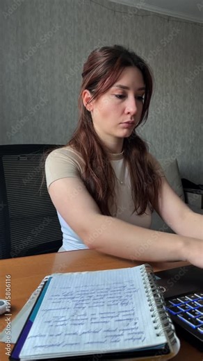 Girl sitting at home at a computer typing on a keyboard while working freelance and preparing for exams in a focused study and remote work environment