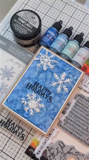 Let’s get ready to make a fun Distress Winter make! Join @JoyOfKrafting as she shares an old school technique using @tim_holtz Alcohol Ink, stamps, dies and a little distress sparkle.✨ Supplies: Tim Holtz Alcohol Ink: -Yupo Cardstock -Alcohol Ink Mini Applicator Felts -Yonder, Bayou, Juniper, Flannel Tim Holtz Distress: -Round Applicator -Archival Ink: Black Soot -Snowflakes Ranger Glossy Accents Tim Holtz Stampers Anonymous Stamps: CMS114 Mini Holidays Tim Holtz Sizzix Dies 665582 Scribbly Snow