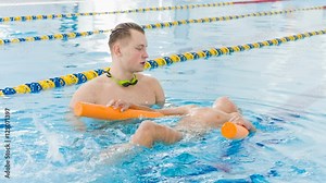 Instructor and child doing exercises in swimming pool. Coach teaches boy to swim