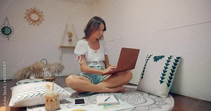 woman works from home she sits in her house room and types on keyboard of her laptop computer
