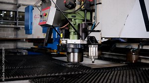 A large industrial punch press forming high precision metal parts. Metal bending machine on a modern industrial factory.