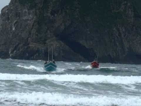Dory boats speeding and landing on beach in Pacific City Oregon