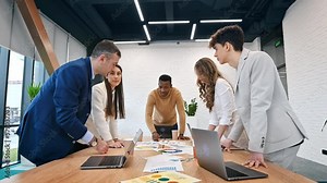 Multiracial group of people at business meeting in an office, discussing business affairs with each other using papers and gadgets on the table