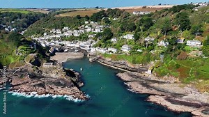 Aerial view over the coastal Polperro village, with seafront houses on a cliff surrounded by nature