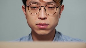 The close-up view of the concentrated chinese man sitting in front of laptop in the office