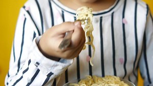 A child eating noodles with a spoon