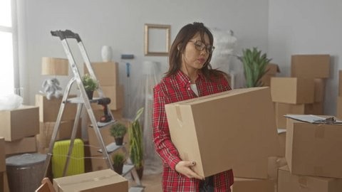 clip-4099385223-woman-lifting-cardboard-box-hands-visible-building