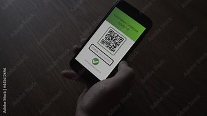 Man in a cafe shows phone with Immune digital passport for covid-19 QR Code