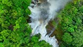 A hidden waterfall nestled in a lush tropical rainforest, captured...