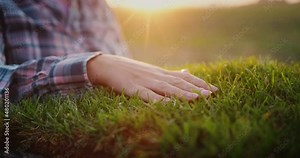 The hand of a female farmer touches a piece of land where green grass grows Stock Video