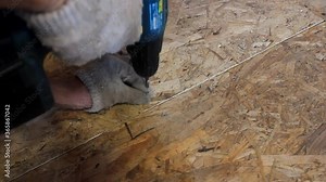 Driving screws into the floor (osb) with a screwdriver. Man's hands