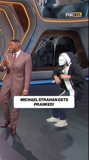 Michael Strahan Startled by On-Air Halloween Scare: ‘That’s How You Get Someone Hurt’ *During a recent broadcast, Michael Strahan experienced a Halloween fright that left him jumping out of his seat. As EW reports, the former NFL player was caught off guard when a masked figure suddenly appeared behind him in a prank that prompted Strahan to recoil in shock. He blurted out, “What’s wrong with you, man?” before realizing it was a joke and breaking into laughter. Cohost Jay Glazer couldn’t stop la