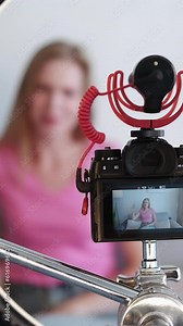 Vertical video. Camera recording. Content filming. Online business. Young smiling female blogger woman on shooting device screen on tripod creating vlog.