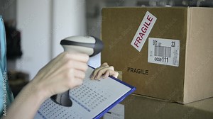 Closeup shot of worker scanning box with barcode reader. Reading and Scanning labels on the boxes with bluetooth barcode scanner in a warehouse.