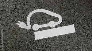 Electric vehicle charging icon on pavement at parking lot on highway road