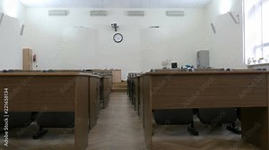Large auditorium, lecture hall, assembly hall, conference hall with rows of chairs and wood desks.