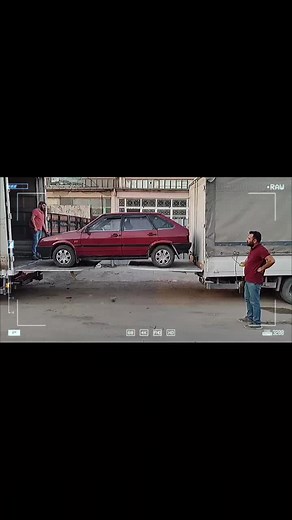 Unloading an Older Model Red Car from a Flatbed Truck