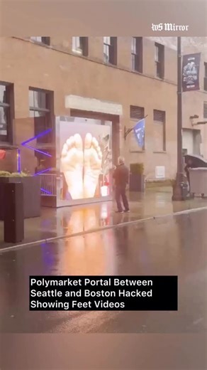 🚨WATCH: @polymarket portal between Seattle and Boston reportedly hacked, displaying feet videos. The public video portal connecting Seattle and Boston, associated with a Polymarket-branded installation, was briefly compromised after users reported that unexpected feet-focused videos appeared on the screen. Footage shared online also shows an elderly man standing in front of the display, taking photos while the content was visible. #wsmirror #polymarket #seattle #boston #hack | Washington Mirror