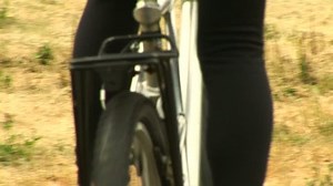 Young woman riding bike through field