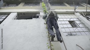 A man with a gas mask comes down from the building ladder and runs away in a destroyed town, concept apocalypse.