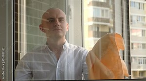 A man cleaning a window using a rag and liquid window cleaner