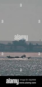 Military personnel navigate inflatable boats near a coastal town, showcasing maritime security operations Stock Video Footage - Alamy