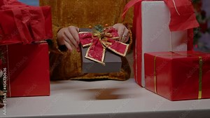 Close up of hand holding present box with ribbon and bow tie for christmas eve festivity. Woman with gifts for family preparing for holiday celebration in december. Seasonal gift
