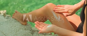 Legs and hands with lotion. Woman applying sunscreen on body at the beach. Self-care routine during a relaxing day at sea.