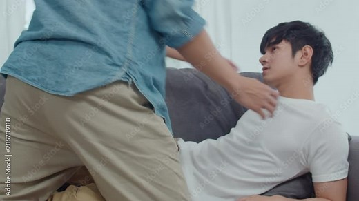 Young Asian Gay couple hug and kiss at home. Attractive Asian LGBTQ pride men happy relax spend romantic time together while lying sofa in living room concept. Slow motion Shot.