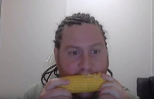Guy with cornrows listens to Korn while eating corn