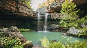 Time-lapse of people swimming in a secluded pool below a waterfall