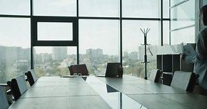 A business professional reviewing documents in a modern conference room with large windows, a scenic city view, and sunlight streaming in, symbolizing strategic planning and analysis